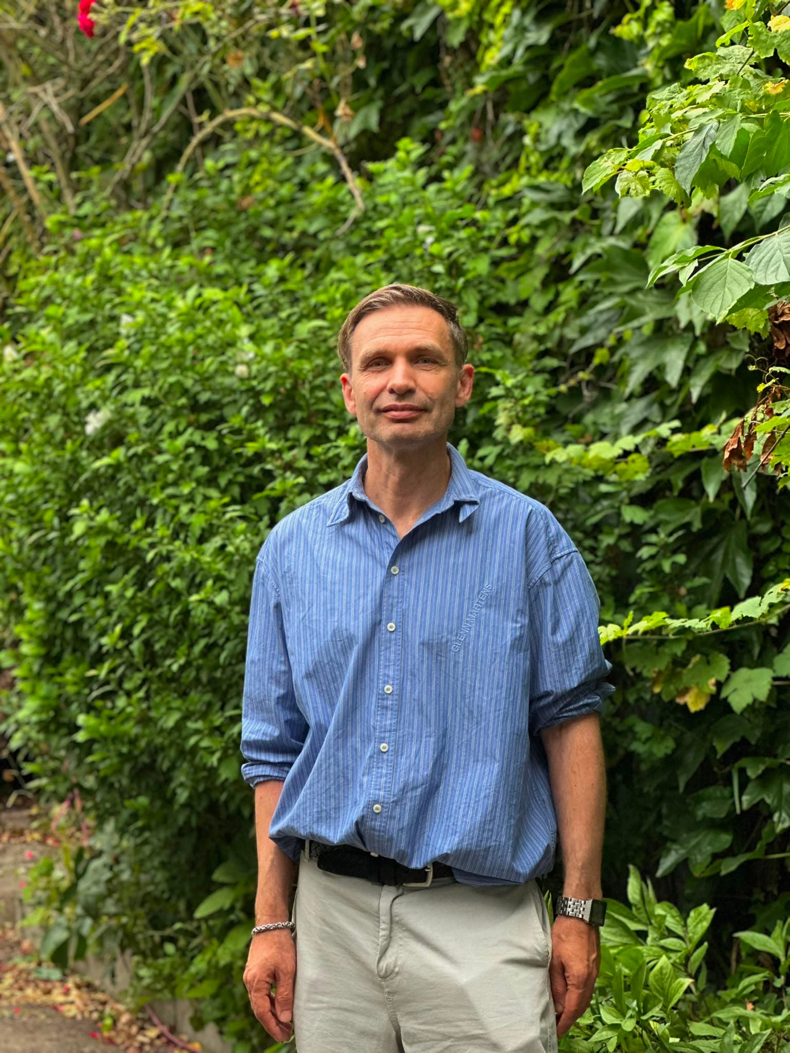 Porträt von Roland Schmitz, Head of Konzeption, Events & Strategie der Rosenhöfe, vor einer efeubewachsenen Wand im Hof